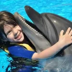 Child hugging and kissing a dolphin at Dolphin World Hurghada.