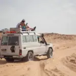 A Jeep carrying tourists in the desert heading towards the Bedouin village on a safari trip.
