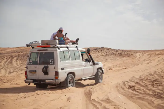 A Jeep carrying tourists in the desert heading towards the Bedouin village on a safari trip.