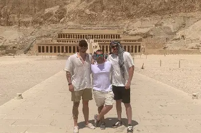 Three young male tourists enjoying a luxury private Luxor tour in front of the historic Hatshepsut Temple in Egypt.
