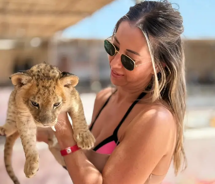Frau mit Sonnenbrille hält ein kleines Löwenbaby in Hurghada